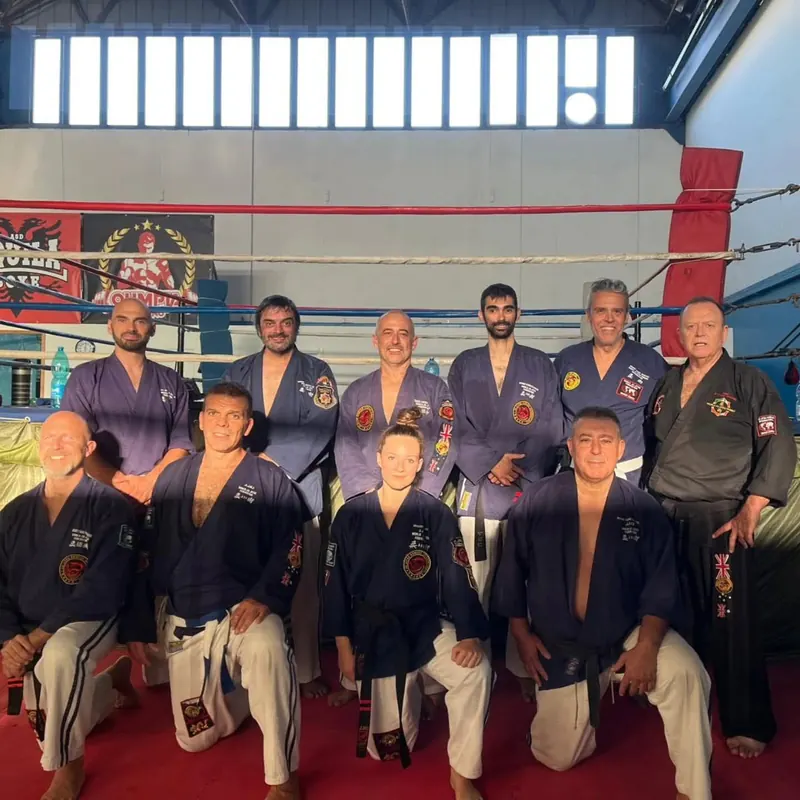 Foto di gruppo in divisa blu, in una palestra con il ring alle spalle