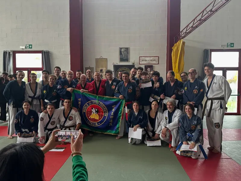 Foto di gruppo a uno stage, con la bandiera della federazione tenuta dagli allievi in prima fila